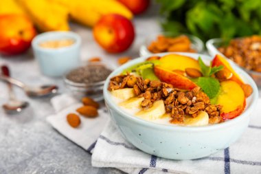 Yoğurt ve taze badem, yaban mersini, ahududu, şeftali, kivi, çilek ve muz ile dokulu mutfak masası. Boşluğu kopyala. Metin için yer.