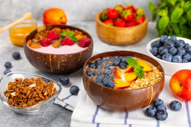 Yoğurt ve taze badem, yaban mersini, ahududu, şeftali ve çilekli granola kasesi mermer mutfak masasında. cai ve spirulina kasesi. Sağlıklı kahvaltı kavramı. Kopya alanı..