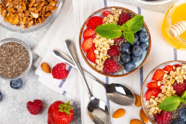 Yoğurt ve taze badem, yaban mersini, ahududu, şeftali ve çilekli granola kasesi mermer mutfak masasında. cai ve spirulina kasesi. Sağlıklı kahvaltı kavramı. Kopya alanı..
