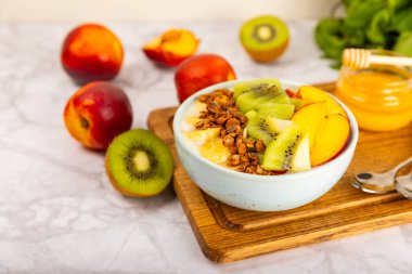 Yoğurt ve taze badem, yaban mersini, ahududu, şeftali, kivi, çilek ve muz ile dokulu mutfak masası. Boşluğu kopyala. Metin için yer.