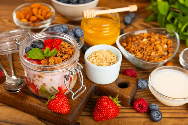 stock image Granola bowl with yogurt and fresh almonds, blueberries, raspberries,peach and strawberries on a brown kitchen table.Acai and spirulina bowl.Healthy breakfast concept.