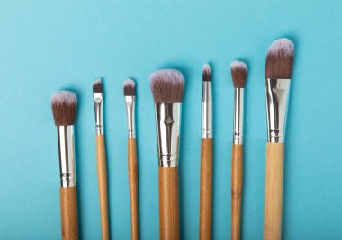 Mavi arka planda kozmetik makyaj fırçası. Makyaj için kozmetik ürün. Yaratıcı ve güzel moda konsepti. Moda. Makyaj fırçası koleksiyonu, üst görünüm, afiş. Metin için yer. 