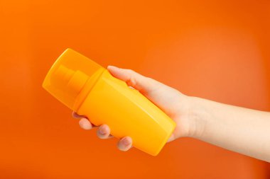 Turuncu arka planda güneş kremi. SPF kremi. Güneş koruması. Ultraviyole koruma. Yaz. Dinlenme ve tatil kavramı. Yaz havası. Tasarım. - Model. Alışveriş konsepti.