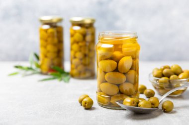 Lezzetli yeşil zeytinler. Cam kavanozda zeytin turşusu. Ahşap bir arka planda. Lezzetli zeytinler. Yakın plan. Vejetaryen. Mesaj için yer. Boşluğu kopyala.