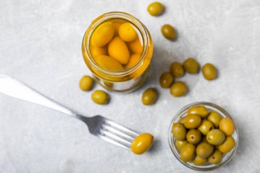 Lezzetli yeşil zeytinler. Cam kavanozda zeytin turşusu. Ahşap bir arka planda. Lezzetli zeytinler. Yakın plan. Vejetaryen. Mesaj için yer. Boşluğu kopyala.