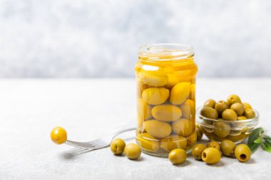 Lezzetli yeşil zeytinler. Cam kavanozda zeytin turşusu. Ahşap bir arka planda. Lezzetli zeytinler. Yakın plan. Vejetaryen. Mesaj için yer. Boşluğu kopyala.