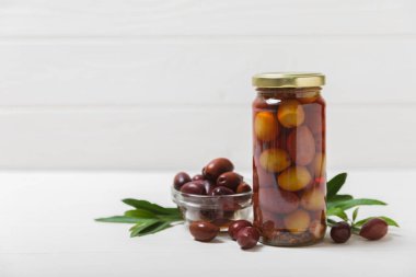 Lezzetli kırmızı zeytinler. Cam kavanozda zeytin turşusu. Ahşap bir arka planda. Lezzetli zeytinler. Yakın plan. Vejetaryen. Mesaj için yer. Boşluğu kopyala.