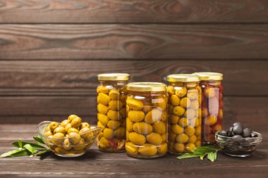 Lezzetli yeşil zeytinler. Cam kavanozda zeytin turşusu. Ahşap bir arka planda. Lezzetli zeytinler. Yakın plan. Vejetaryen. Mesaj için yer. Boşluğu kopyala.