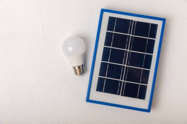 Güneş paneli, lamba, para ve doku arka planında domuz kumbarası olan düz bir kompozisyon. Tasarruf ve temiz enerji kavramı. Ekoloji ve sürdürülebilir gelişme kavramı. Teknolojiler.