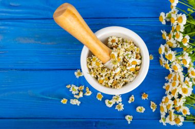 Havanda papatya çiçekleri ahşap bir masada. Şifalı bitkiler. Alternatif tıp. İyileşiyor. Homeopati. Doğal bitkisel kozmetik konsepti. Doğal çay. Uzayı kopyala Düz yatıyordu