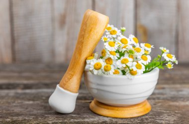 Havanda papatya çiçekleri ahşap bir masada. Şifalı bitkiler. Alternatif tıp. İyileşiyor. Homeopati. Doğal bitkisel kozmetik konsepti. Doğal çay. Uzayı kopyala Düz yatıyordu