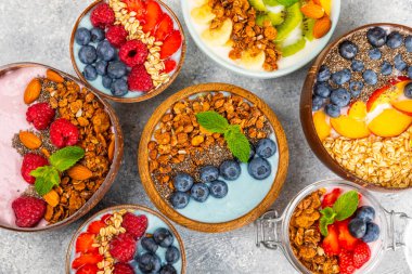 Bir kase granola yoğurt ve dokuma masasında taze böğürtlen. Yoğurt böğürtlen, acai kasesi, spirulina kasesi. Sağlıklı yemek, dengeli kahvaltı. Çilek, yabanmersini, kivi, şeftali, badem ve chia..
