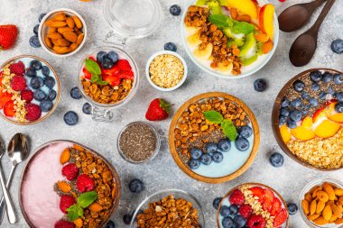 Bir kase granola yoğurt ve dokuma masasında taze böğürtlen. Yoğurt böğürtlen, acai kasesi, spirulina kasesi. Sağlıklı yemek, dengeli kahvaltı. Çilek, yabanmersini, kivi, şeftali, badem ve chia..