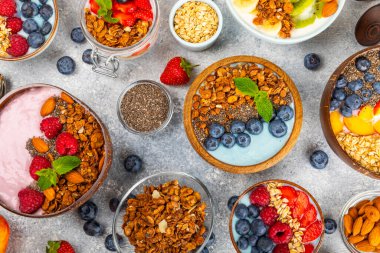 Bir kase granola yoğurt ve dokuma masasında taze böğürtlen. Yoğurt böğürtlen, acai kasesi, spirulina kasesi. Sağlıklı yemek, dengeli kahvaltı. Çilek, yabanmersini, kivi, şeftali, badem ve chia..