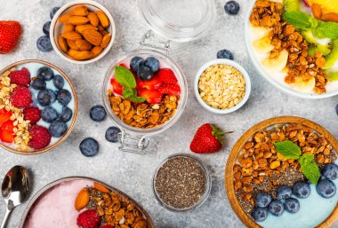 Bir kase granola yoğurt ve dokuma masasında taze böğürtlen. Yoğurt böğürtlen, acai kasesi, spirulina kasesi. Sağlıklı yemek, dengeli kahvaltı. Çilek, yabanmersini, kivi, şeftali, badem ve chia..