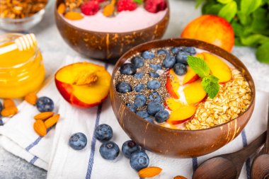 Bir kase granola yoğurt ve dokuma masasında taze böğürtlen. Yoğurt böğürtlen, acai kasesi, spirulina kasesi. Sağlıklı yemek, dengeli kahvaltı. Çilek, yabanmersini, kivi, şeftali, badem ve chia..