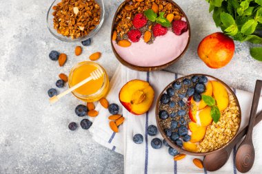 Bir kase granola yoğurt ve dokuma masasında taze böğürtlen. Yoğurt böğürtlen, acai kasesi, spirulina kasesi. Sağlıklı yemek, dengeli kahvaltı. Çilek, yabanmersini, kivi, şeftali, badem ve chia..