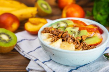 Bir kase granola yoğurt ve dokuma masasında taze böğürtlen. Yoğurt böğürtlen, acai kasesi, spirulina kasesi. Sağlıklı yemek, dengeli kahvaltı. Çilek, yabanmersini, kivi, şeftali, badem ve chia..