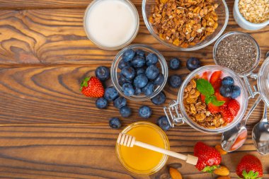 Bir kase granola yoğurt ve dokuma masasında taze böğürtlen. Yoğurt böğürtlen, acai kasesi, spirulina kasesi. Sağlıklı yemek, dengeli kahvaltı. Çilek, yabanmersini, kivi, şeftali, badem ve chia..