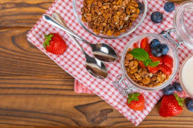 Bir kase granola yoğurt ve dokuma masasında taze böğürtlen. Yoğurt böğürtlen, acai kasesi, spirulina kasesi. Sağlıklı yemek, dengeli kahvaltı. Çilek, yabanmersini, kivi, şeftali, badem ve chia..