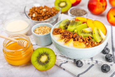 Bir kase granola yoğurt ve dokuma masasında taze böğürtlen. Yoğurt böğürtlen, acai kasesi, spirulina kasesi. Sağlıklı yemek, dengeli kahvaltı. Çilek, yabanmersini, kivi, şeftali, badem ve chia..