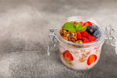 Bir kase granola yoğurt ve dokuma masasında taze böğürtlen. Yoğurt böğürtlen, acai kasesi, spirulina kasesi. Sağlıklı yemek, dengeli kahvaltı. Çilek, yabanmersini, kivi, şeftali, badem ve chia..