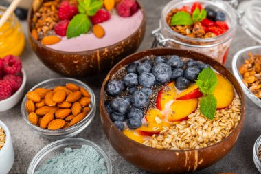 Bir kase granola yoğurt ve dokuma masasında taze böğürtlen. Yoğurt böğürtlen, acai kasesi, spirulina kasesi. Sağlıklı yemek, dengeli kahvaltı. Çilek, yabanmersini, kivi, şeftali, badem ve chia..
