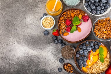 Bir kase granola yoğurt ve dokuma masasında taze böğürtlen. Yoğurt böğürtlen, acai kasesi, spirulina kasesi. Sağlıklı yemek, dengeli kahvaltı. Çilek, yabanmersini, kivi, şeftali, badem ve chia..