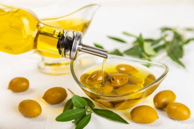 Şişede zeytinyağı ve mutfak masasında sos kabı. Zeytin dallı ve meyveli yağ şişesi. Mesaj için yer. kopyalama alanı. sebze yağı ve salata sosu..