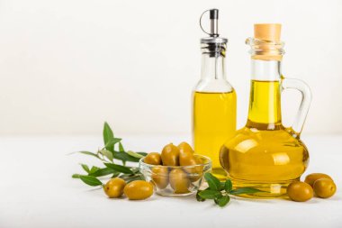 Şişede zeytinyağı ve mutfak masasında sos kabı. Zeytin dallı ve meyveli yağ şişesi. Mesaj için yer. kopyalama alanı. sebze yağı ve salata sosu..