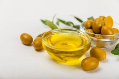 Şişede zeytinyağı ve mutfak masasında sos kabı. Zeytin dallı ve meyveli yağ şişesi. Mesaj için yer. kopyalama alanı. sebze yağı ve salata sosu..