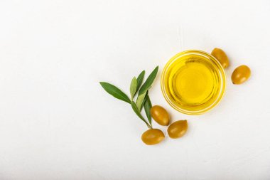 Şişede zeytinyağı ve mutfak masasında sos kabı. Zeytin dallı ve meyveli yağ şişesi. Mesaj için yer. kopyalama alanı. sebze yağı ve salata sosu..