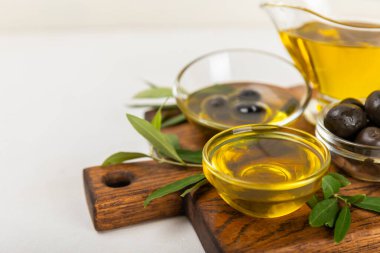 Şişede zeytinyağı ve mutfak masasında sos kabı. Zeytin dallı ve meyveli yağ şişesi. Mesaj için yer. kopyalama alanı. sebze yağı ve salata sosu..