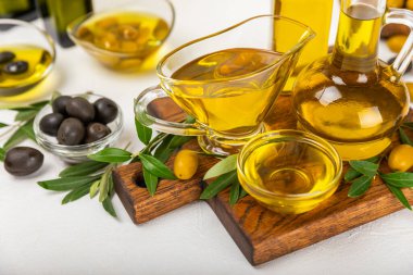 Şişede zeytinyağı ve mutfak masasında sos kabı. Zeytin dallı ve meyveli yağ şişesi. Mesaj için yer. kopyalama alanı. sebze yağı ve salata sosu..