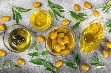 Şişede zeytinyağı ve mutfak masasında sos kabı. Zeytin dallı ve meyveli yağ şişesi. Mesaj için yer. kopyalama alanı. sebze yağı ve salata sosu..