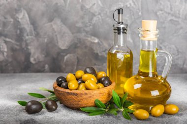 Şişede zeytinyağı ve mutfak masasında sos kabı. Zeytin dallı ve meyveli yağ şişesi. Mesaj için yer. kopyalama alanı. sebze yağı ve salata sosu..