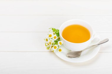 Beyaz bir masada papatya çayı. Lezzetli tonik, rahatlatıcı ve papatya çayı, papatya çiçekleri, bal ve limon. Dokunulmazlık için bitki çayı. Yakın çekim. Mesaj için yer. Boşluğu kopyala.