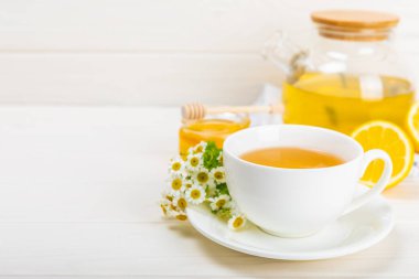 Beyaz bir masada papatya çayı. Lezzetli tonik, rahatlatıcı ve papatya çayı, papatya çiçekleri, bal ve limon. Dokunulmazlık için bitki çayı. Yakın çekim. Mesaj için yer. Boşluğu kopyala.