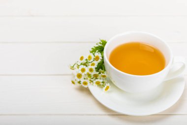 Beyaz bir masada papatya çayı. Lezzetli tonik, rahatlatıcı ve papatya çayı, papatya çiçekleri, bal ve limon. Dokunulmazlık için bitki çayı. Yakın çekim. Mesaj için yer. Boşluğu kopyala.