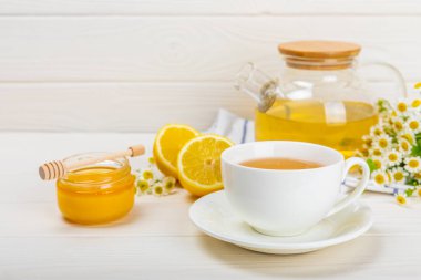 Beyaz bir masada papatya çayı. Lezzetli tonik, rahatlatıcı ve papatya çayı, papatya çiçekleri, bal ve limon. Dokunulmazlık için bitki çayı. Yakın çekim. Mesaj için yer. Boşluğu kopyala.