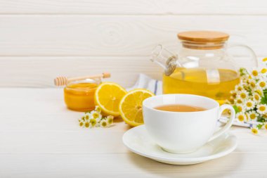 Beyaz bir masada papatya çayı. Lezzetli tonik, rahatlatıcı ve papatya çayı, papatya çiçekleri, bal ve limon. Dokunulmazlık için bitki çayı. Yakın çekim. Mesaj için yer. Boşluğu kopyala.