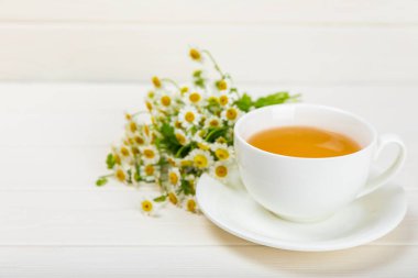 Beyaz bir masada papatya çayı. Lezzetli tonik, rahatlatıcı ve papatya çayı, papatya çiçekleri, bal ve limon. Dokunulmazlık için bitki çayı. Yakın çekim. Mesaj için yer. Boşluğu kopyala.