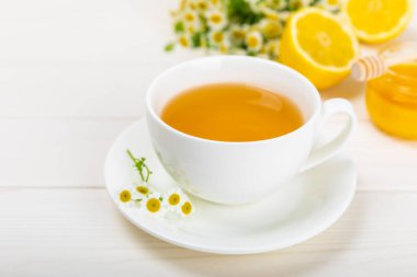 Beyaz bir masada papatya çayı. Lezzetli tonik, rahatlatıcı ve papatya çayı, papatya çiçekleri, bal ve limon. Dokunulmazlık için bitki çayı. Yakın çekim. Mesaj için yer. Boşluğu kopyala.