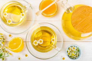 Beyaz bir masada papatya çayı. Lezzetli tonik, rahatlatıcı ve papatya çayı, papatya çiçekleri, bal ve limon. Dokunulmazlık için bitki çayı. Yakın çekim. Mesaj için yer. Boşluğu kopyala.