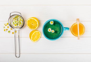 Beyaz bir masada papatya çayı. Lezzetli tonik, rahatlatıcı ve papatya çayı, papatya çiçekleri, bal ve limon. Dokunulmazlık için bitki çayı. Yakın çekim. Mesaj için yer. Boşluğu kopyala.