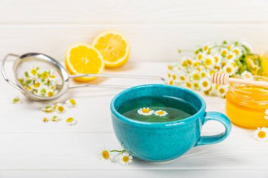 Beyaz bir masada papatya çayı. Lezzetli tonik, rahatlatıcı ve papatya çayı, papatya çiçekleri, bal ve limon. Dokunulmazlık için bitki çayı. Yakın çekim. Mesaj için yer. Boşluğu kopyala.