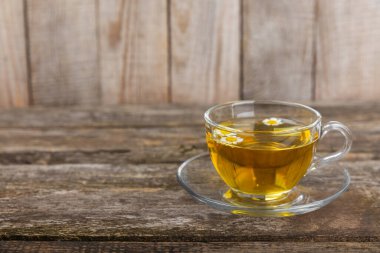 Kahverengi bir masada papatya çayı. Lezzetli tonik, rahatlatıcı ve papatya çayı, papatya çiçekleri, bal ve limon. Dokunulmazlık için bitki çayı. Yakın çekim. Mesaj için yer. Boşluğu kopyala.