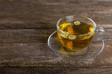 Kahverengi bir masada papatya çayı. Lezzetli tonik, rahatlatıcı ve papatya çayı, papatya çiçekleri, bal ve limon. Dokunulmazlık için bitki çayı. Yakın çekim. Mesaj için yer. Boşluğu kopyala.