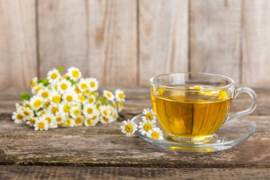 Kahverengi bir masada papatya çayı. Lezzetli tonik, rahatlatıcı ve papatya çayı, papatya çiçekleri, bal ve limon. Dokunulmazlık için bitki çayı. Yakın çekim. Mesaj için yer. Boşluğu kopyala.