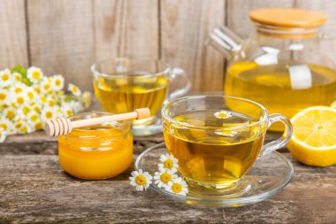 Kahverengi bir masada papatya çayı. Lezzetli tonik, rahatlatıcı ve papatya çayı, papatya çiçekleri, bal ve limon. Dokunulmazlık için bitki çayı. Yakın çekim. Mesaj için yer. Boşluğu kopyala.
